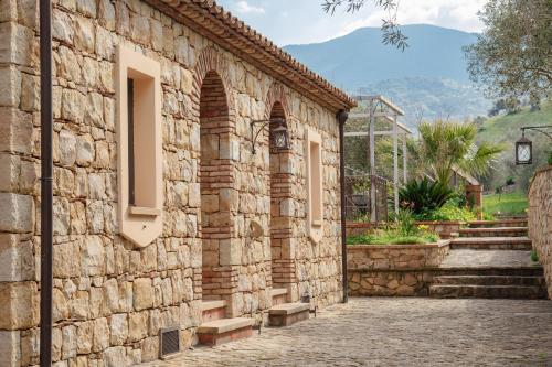 a stone facade of a building with a mountain in the background at Azienda Agrituristica Bergi in Castelbuono