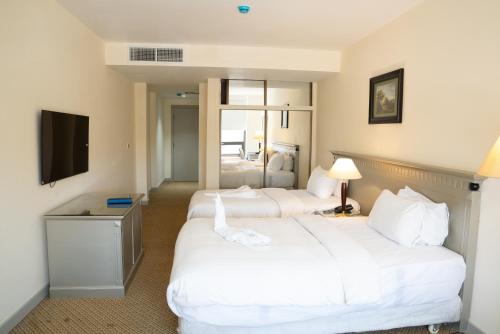 a hotel room with two beds and a television at Armada Avenue Hotel Amman in Amman