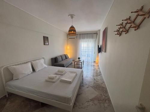 a white bedroom with a bed and a couch at Summer Holidays in Nea Kalikratia