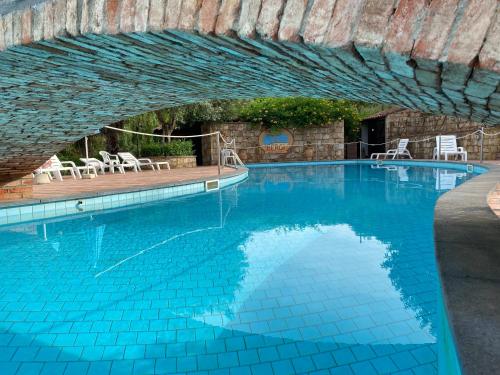 a large swimming pool with a brick wall and blue water at Azienda Agrituristica Bergi in Castelbuono