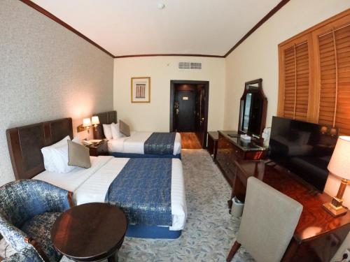 a hotel room with two beds and a couch at Knight Armour Hotel in Dubai