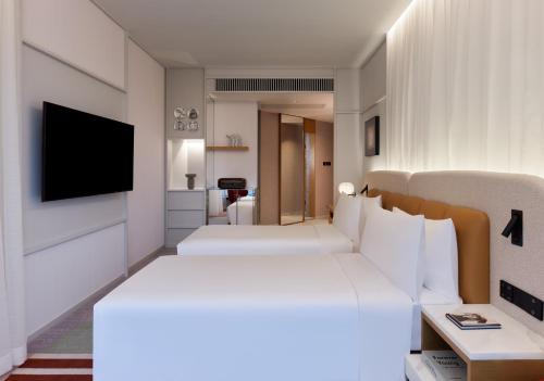 a hotel room with two beds and a flat screen tv at Mondrian Hong Kong in Hong Kong