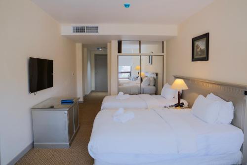 a hotel room with two beds and a television at Armada Avenue Hotel Amman in Amman