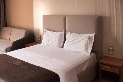 a bedroom with a bed with white sheets and pillows at Hotel Platinium Dhermi in Vlorë