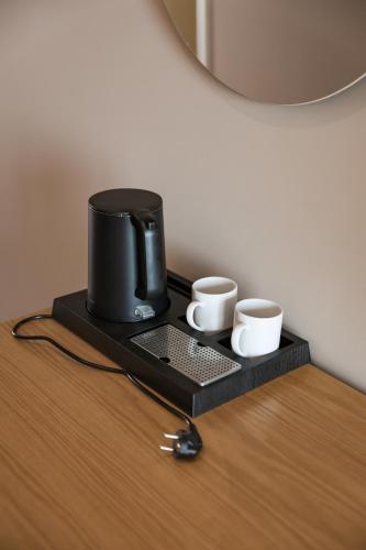 a coffee maker and two cups on a table at Hotel Platinium Dhermi in Vlorë