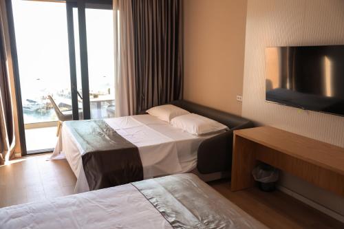 a hotel room with two beds and a flat screen tv at Hotel Platinium Dhermi in Vlorë