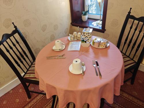 a pink table with plates and utensils on it at The Jays Guest House in Aberdeen