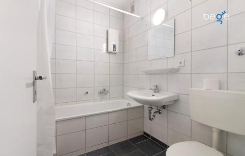 a white tiled bathroom with a sink and a toilet at BEGE APARTMENTS WorkPoint in Dorsten