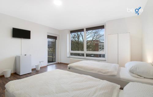 a white bedroom with two beds and a window at BEGE APARTMENTS WorkPoint in Dorsten