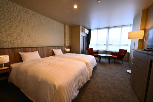 a hotel room with a bed and a table and chairs at ホテルグランリゾート蓼科 in Chino