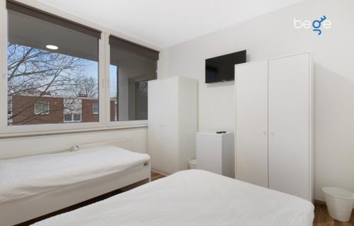 a white bedroom with two beds and a window at BEGE APARTMENTS WorkPoint in Dorsten
