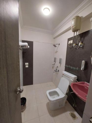 a bathroom with a toilet and a pink sink at Outstay Executive Apartments in Navi Mumbai