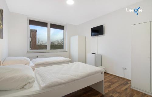 two beds in a white room with a window at BEGE APARTMENTS WorkPoint in Dorsten