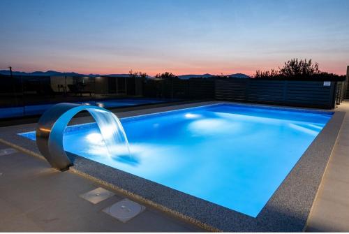 a large swimming pool with a blue lit up swimming poolvisor at Luxury Grey house in Stolac