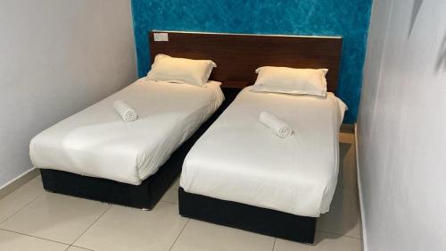 two beds with white sheets and pillows in a room at Codidik Hotel in Kuantan