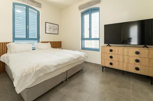 a bedroom with a large bed and a flat screen tv at UG Boutique - סוויטות מדהימות ומעוצבות מול הכנרת in Tiberias