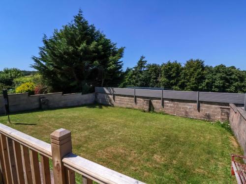 a backyard with a retaining wall and a lawn at West View in Okehampton