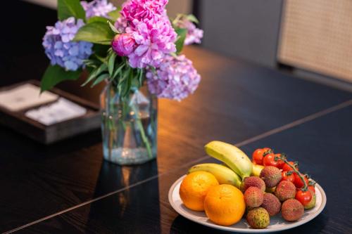 a plate of fruit on a table with a vase of flowers at Yi Nian · Fangcun Hotel in Nanchang