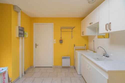 a kitchen with yellow walls and a white sink at Maison Individuelle, Royan Centre in Royan