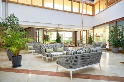 a lobby with couches and tables and plants at Aparthotel Duva & Spa in Port de Pollensa