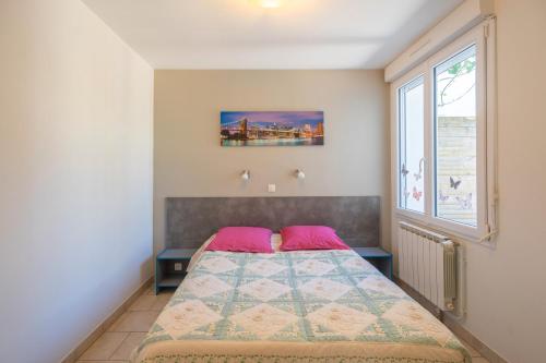 a bedroom with a bed with pink pillows and a window at Maison Individuelle, Royan Centre in Royan