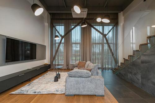 un salon avec une télévision, un canapé et des chaises dans l'établissement Parko namai-loftas, à Kaunas