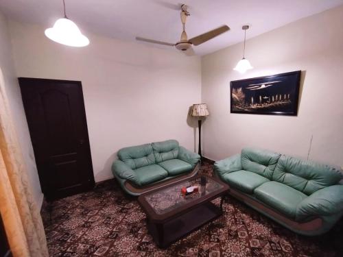 a living room with two green couches and a table at Hilltop Totel in Karachi