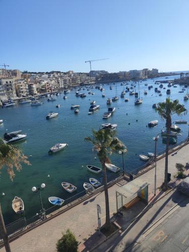 a group of boats in a river with buildings at Bay Seafront Apartment in Marsaskala