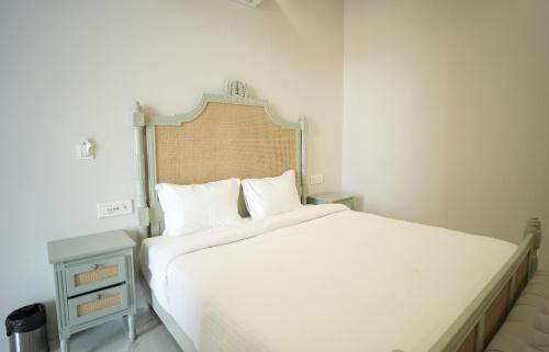 a bedroom with a large white bed with a wooden headboard at Angelo's farm in Jaipur