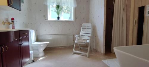 a bathroom with a toilet and a chair and a window at Lottefors Logi in Bollnäs