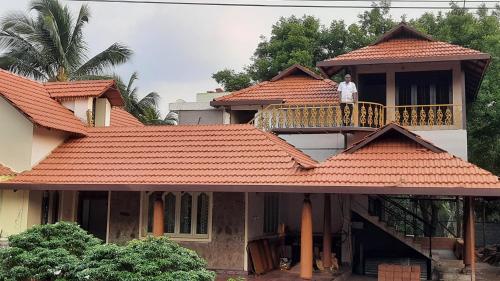a man standing on the balcony of a house at Yes Yes Farms in Pollāchi