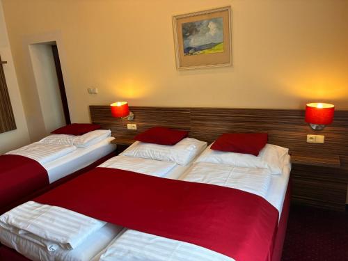 two beds in a hotel room with red lamps at Hotel Continental in Plzeň