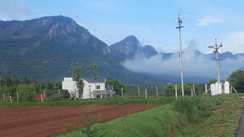 a house on a dirt road with mountains in the background at Yes Yes Farms in Pollāchi