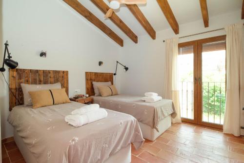zwei Betten in einem Zimmer mit Fenster in der Unterkunft Alojamiento rural La Mula en pleno corazón de la montaña de Alicante in Patró