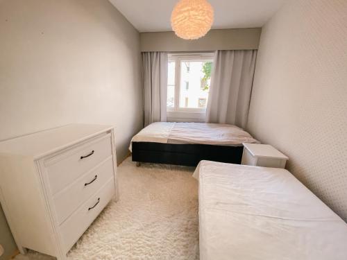 a bedroom with two beds and a dresser and a window at Beautiful home close to the sea and city center in Helsinki