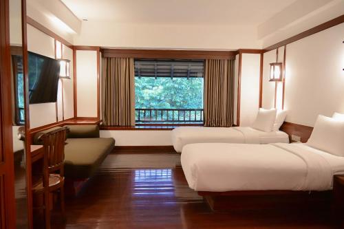 a hotel room with two beds and a window at Novotel Bogor Golf Resort in Bogor