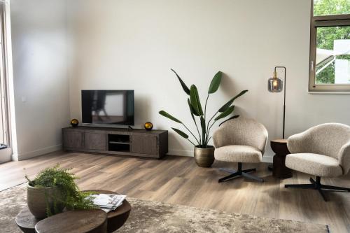 a living room with two chairs and a television at Kooparc vakantiepark in Giesbeek