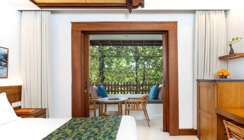 a room with a bed and a table and a window at Legian Beach Hotel in Legian