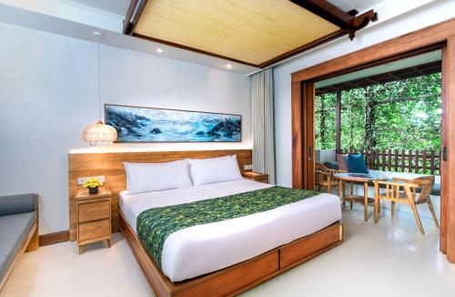 a bedroom with a bed and a table and chairs at Legian Beach Hotel in Legian