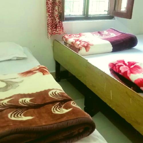 two beds sitting in a room with a window at The Misty Hotel in Bhatwāri