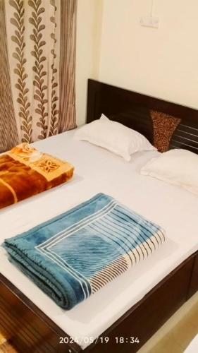 a white bed with a blue towel on it at The Misty Hotel in Bhatwāri