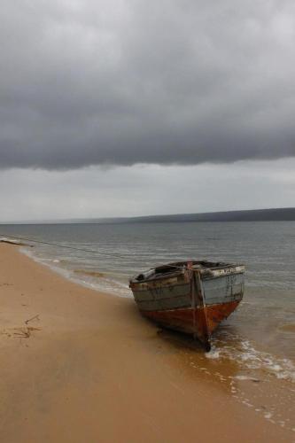 a boat sitting on the shore of a beach at Linga Bay Retreat in Morrumbene
