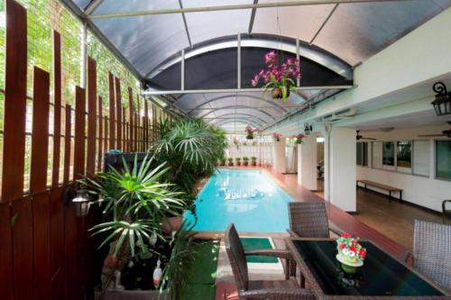 an indoor swimming pool with plants in a building at Nara Poshtel Sathorn in Bangkok