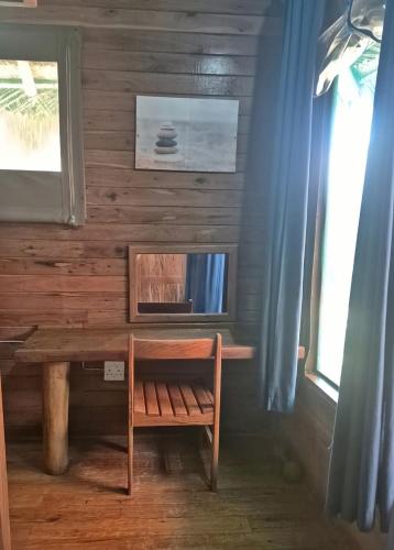 a wooden table with a bench next to a window at Linga Bay Retreat in Morrumbene
