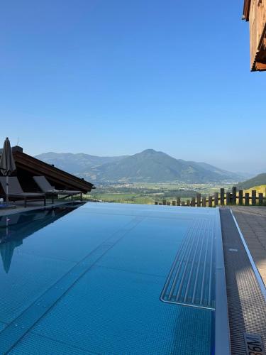 a swimming pool with blue water and mountains in the background at ZAGLGUT HOTEL-CHALETS Wellness & Views with Summer Card Included in Kaprun