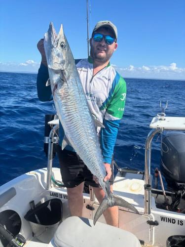a man standing on a boat holding a fish at Linga Bay Retreat in Morrumbene