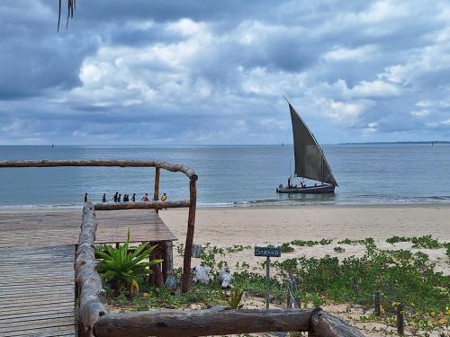 a boat on the beach with a sail boat in the water at Linga Bay Retreat in Morrumbene
