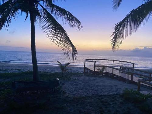 a beach with palm trees and the ocean at sunset at Linga Bay Retreat in Morrumbene