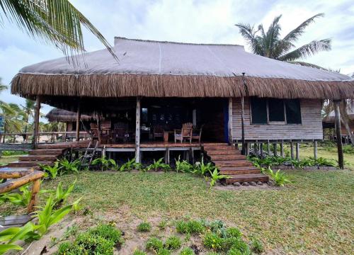 a house with a thatched roof and a porch at Linga Bay Retreat in Morrumbene