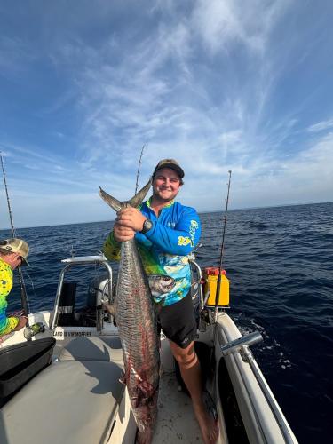 a man on a boat holding a large fish at Linga Bay Retreat in Morrumbene
